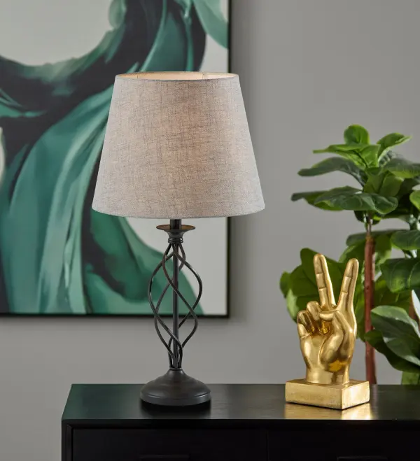 The Darcy Table Lamp combines modern sculptural design with practical functionality. Its distinctive open spiral metal base creates visual interest while the textured grey fabric shade softens light for ambient illumination. - alternate view