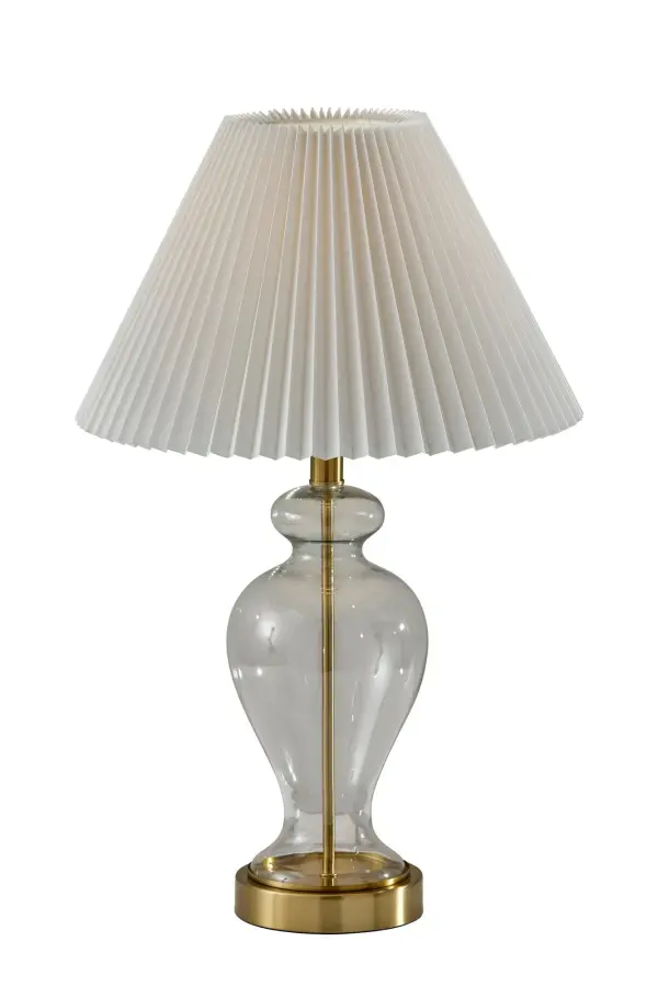 The Sonata Table Lamp blends vintage charm with modern functionality through its clear glass base and antique brass accents. The off-white pleated shade creates soft, inviting illumination perfect for bedside or desk use.