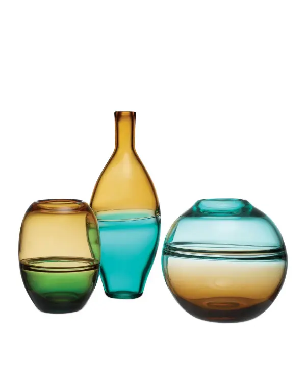 This trio of mouth-blown glass vases showcases exceptional artisan craftsmanship with vibrant dual-tone colorways. Each piece features organic curves and distinctive color transitions where two artisans simultaneously blow different colored glass into the same mold.