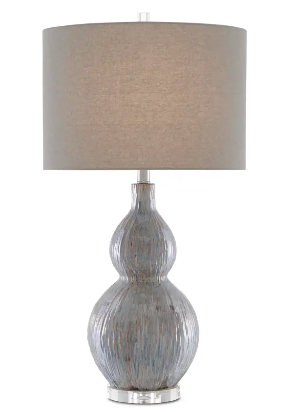 The Idyll Table Lamp combines artisanal porcelain craftsmanship with sophisticated coastal styling. Its striated gray, blue, and taupe finish creates visual depth, while the clear crystal base adds refined elegance.