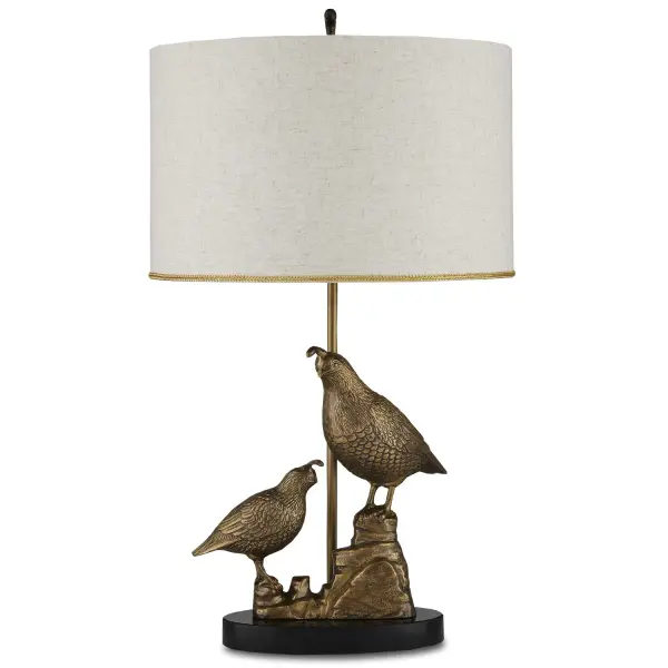 This distinctive table lamp features hand-cast aluminum quail perched on a rocky ledge, combining artisanal craftsmanship with functional lighting. The antique brass finish and honed black marble base create sophisticated contrast, while the natural linen shade with gold foil lining provides warm, ambient illumination.