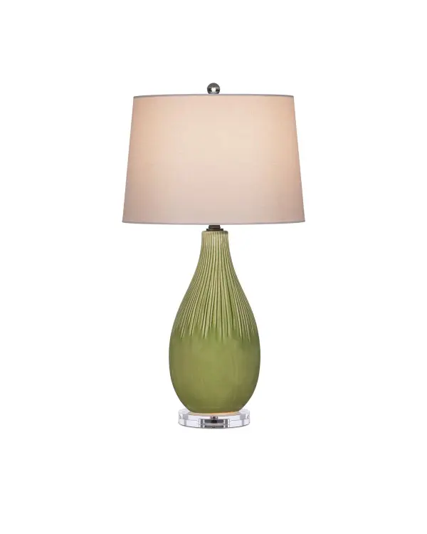 The Anjou Table Lamp combines artisanal craftsmanship with sophisticated materials. Its hand-glazed pale green ceramic body features carved striations that create visual texture, while optic crystal base and finial add luminous elegance. The warm satin brass hardware and natural linen shade complete this refined transitional design.