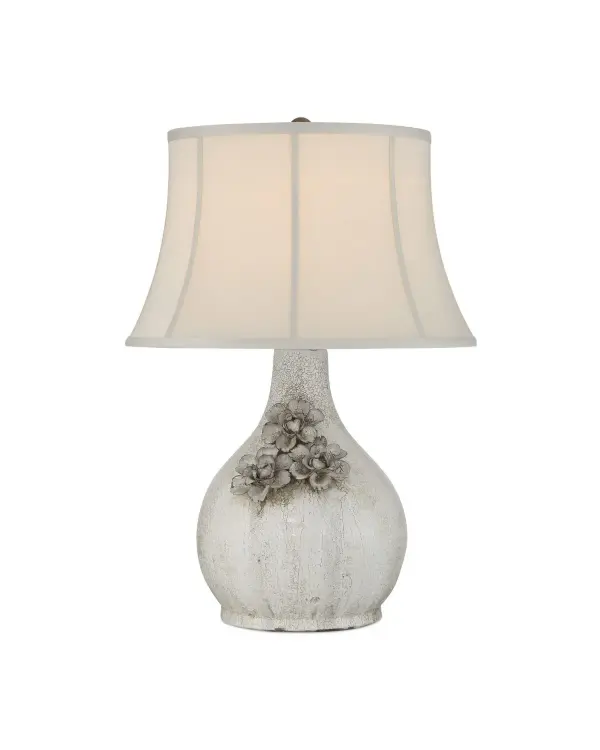 The Attar table lamp showcases exceptional craftsmanship with its crackled ceramic finish and hand-applied floral details. Each piece has unique character due to the artisanal glazing technique. The soft bell shade balances the textured base beautifully.