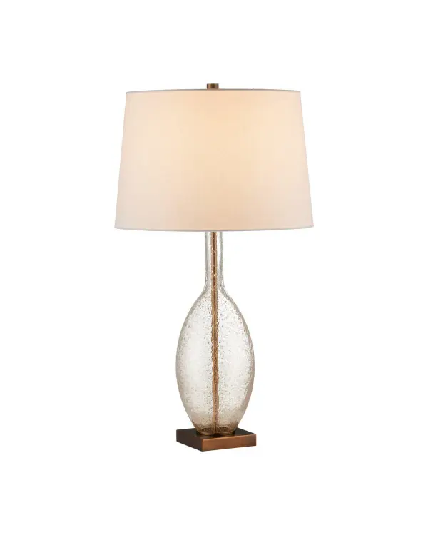 The Adularia combines artisanal glasswork with refined metalwork, featuring a transparent column with suspended particulate matter that creates unique visual depth. The dark bronze base grounds the luminous glass body, offering sophisticated ambiance.