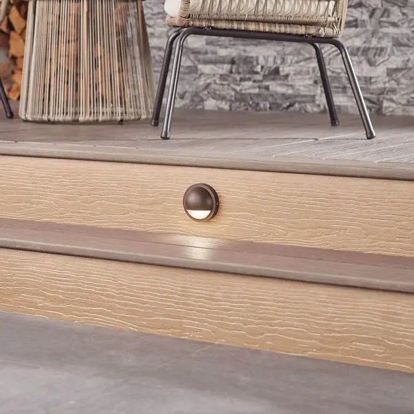 This low-profile deck light delivers warm 2700K illumination with integrated LED efficiency. Wet-rated for all-weather performance, its textured bronze finish complements outdoor living spaces while providing subtle accent lighting. - alternate view