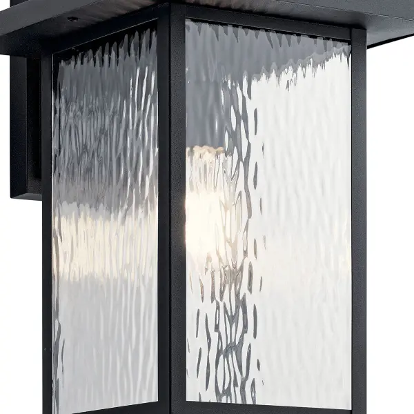 The Capanna Outdoor Wall Light combines textured black finish with clear water glass for a transitional look that works in both residential and commercial settings. Wet-rated and dimmable for versatile outdoor use. - alternate view