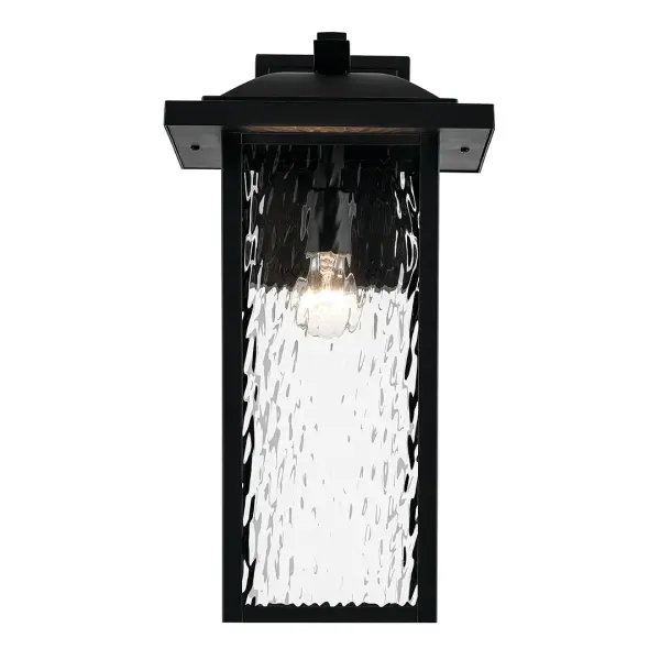 The Capanna outdoor wall light combines transitional style with durable wet-rated construction. Its textured black finish and clear water glass shade create visual interest while providing reliable illumination for exterior spaces. - alternate view