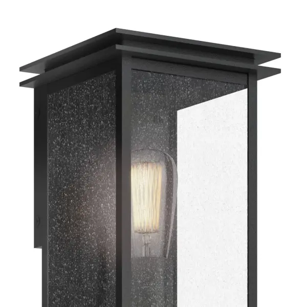The Arkville outdoor wall light combines rustic farmhouse charm with practical outdoor durability. Its black textured finish and seeded glass shade create warm, inviting illumination perfect for entryways and porches. - alternate view