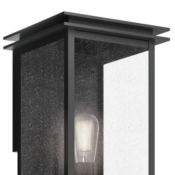 The Arkville outdoor wall light combines rustic farmhouse charm with durable wet-rated construction. Its black textured finish and seeded glass shade create warm, inviting illumination for entryways and outdoor living spaces. - alternate view