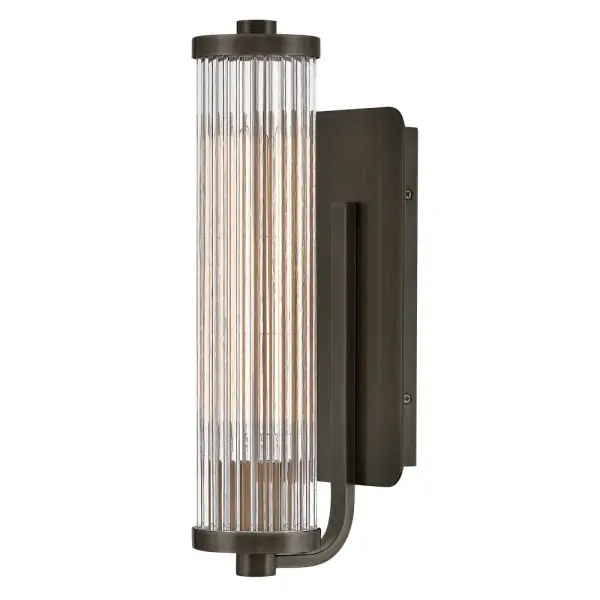 A touch of modern style and vintage charm, Ellery’s Clear glass shade is composed of tall cylindrical glass rods, creating a beautiful reeded effect when illuminated. A large rectangular backplate and matching end caps are finished in a Black Oxide, Heritage Brass, or Polished Nickel finish that complements any bath or living space.
