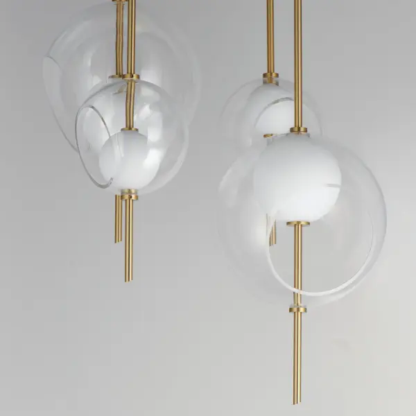 The Martini pendant brings class and character with its distinctive layered glass globe design. Clear outer globes with slanted openings reveal smaller white glass spheres illuminated by integrated LED lights, creating visual depth and modern elegance. - alternate view