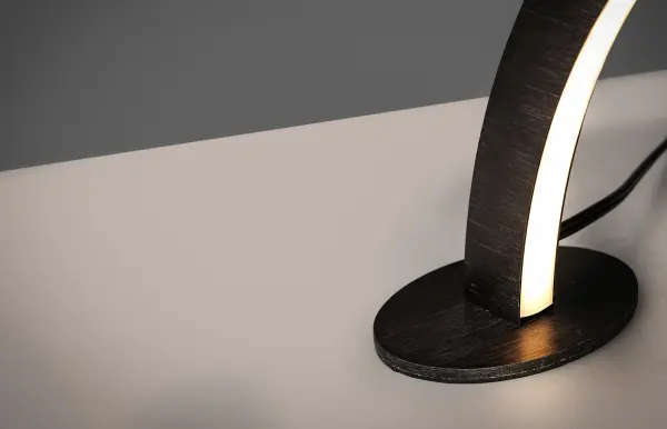 This contemporary table lamp features a unique arc design in brushed black aluminum. With 1600 lumens of warm LED light, it's perfect for task lighting on desks or as an accent on console tables. - alternate view