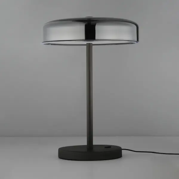 The Voto LED Table Lamp features innovative edge-lit technology within shallow glass domes, creating a striking visual effect while delivering efficient, evenly distributed illumination. Its minimalist gunmetal frame conceals all hardware for a clean, contemporary aesthetic. - alternate view