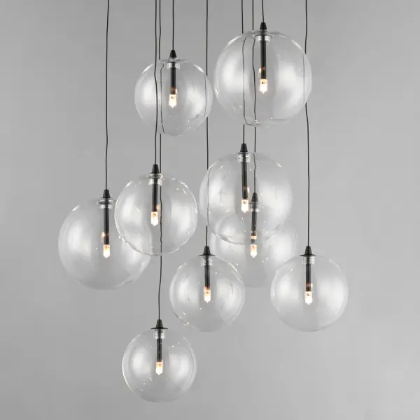The Global chandelier features nine clear blown glass globes in varying sizes suspended on delicate low-voltage wires, creating an airy, floating effect. Energy-efficient G4 LED lamps provide warm illumination through the transparent spheres. - alternate view