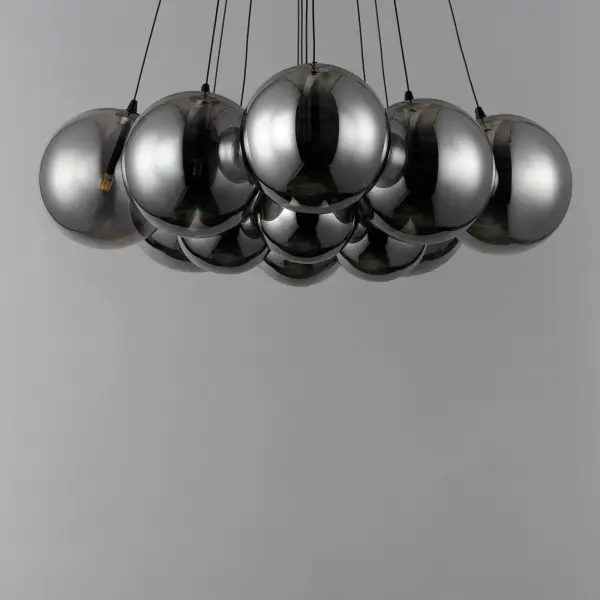 The Burst pendant features 12 smoke glass globes in varied sizes that radiate from a central point, creating a sculptural statement piece. Matte black frame and cables provide bold contrast while integrated LED G4 lamps offer energy-efficient illumination. - alternate view