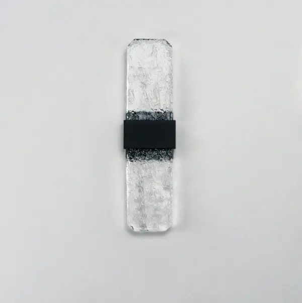 The Rune Large Wall Sconce showcases handcrafted cast glass slabs with unique imperfections, illuminated by concealed LED lighting. Its durable aluminum construction and outdoor-rated black finish make it ideal for exterior applications. - alternate view