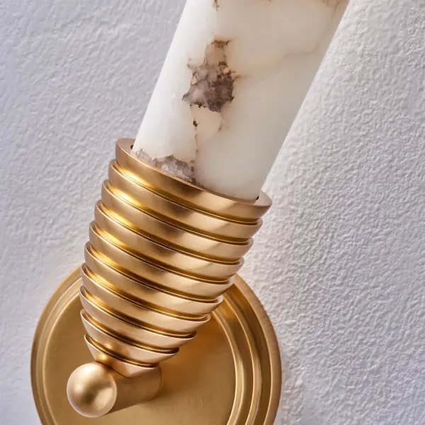 Botanically inspired by Pinecone shapes, the soft Art Deco design of the Gypsum wall sconce features a cylindrical slightly bulged natural Alabaster stone cylinder that diffuses the LED light and gives the fixture a softer luxurious look. Offered in True Brass with driverless LED technology. Collection: Gypsum Rooms: Powder Room, Dining Room, Living Room, Bathroom Finish: True Brass Width: 5.00" Height: 23.00" Extension from Wall: 4.00" Wire: 12" Canopy: 5"x0.5" Bulbs Included Maximum Wattage: 8.00 W Bulb Type: LED Bulb Base: Integrated Light Source: LED Light Output: 560.00 lm Color Temperature: 3000 K CRI: 90 Dimmable Voltage: 120.00 V Material: Brass, Alabaster Country of Origin: China Safety Listing: UL-cUL Safety Rating: Dry ADA LED - alternate view