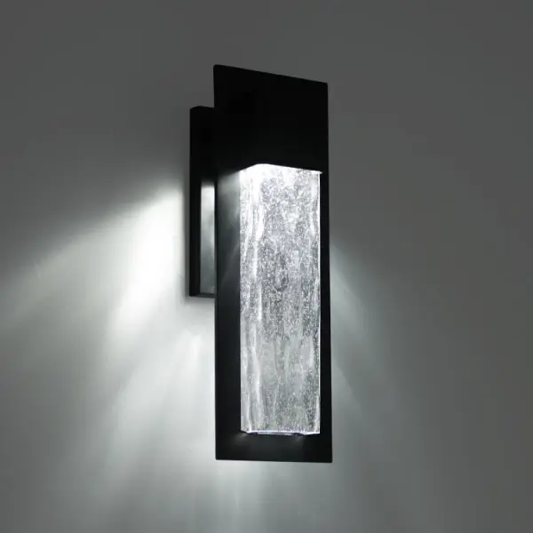 The Mist outdoor wall sconce combines colonial-era craftsmanship with modern LED efficiency. Its 25-inch height makes a bold architectural statement, while hammered seedy glass creates captivating light patterns. Weather-resistant construction and 90 CRI ensure lasting beauty and quality illumination.