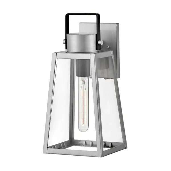 The Hugh outdoor wall lantern delivers sophisticated transitional design with its trapezoidal silhouette and oversized clear glass panes. Two-tone metal finishes add contemporary flair while vintage filament bulbs enhance its visual impact.
