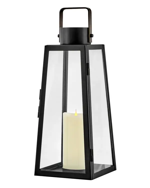 The Hugh Decorative Lantern combines bold trapezoidal design with oversized clear glass panes and a sleek black metal frame. Battery-operated LED faux flame candle included for versatile placement without wiring.