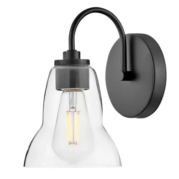 The Vera vanity light elevates traditional bell-shaped design with a unique, shapely form. Clear glass provides excellent up and down illumination, making it ideal for both main baths and powder rooms. The sleek black finish adds modern sophistication.