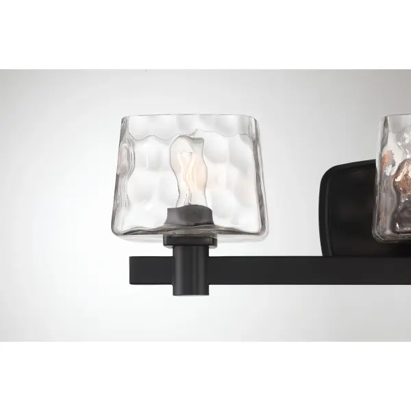 The Drysdale 3-light vanity combines industrial charm with modern functionality. Its coal black finish and hammered glass shades create visual interest, while the reversible mounting offers installation flexibility. - alternate view