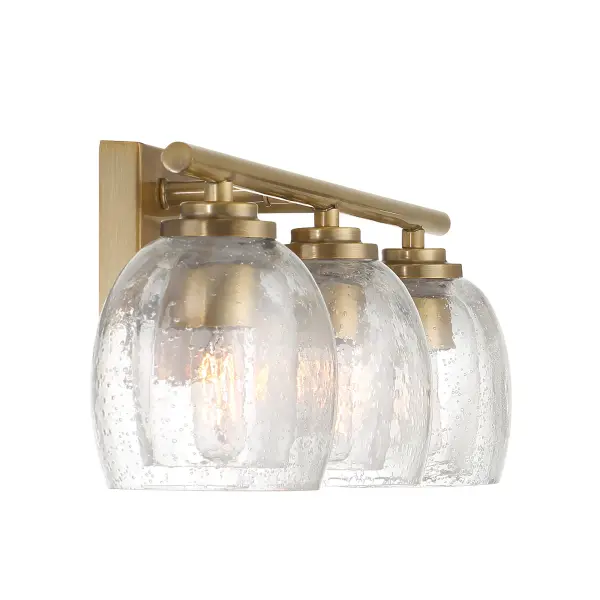 The Glint 24" vanity light combines transitional elegance with practical illumination. Legacy brass finish and clear seeded glass shades create sophisticated ambiance perfect for modern and traditional bathrooms alike. - alternate view