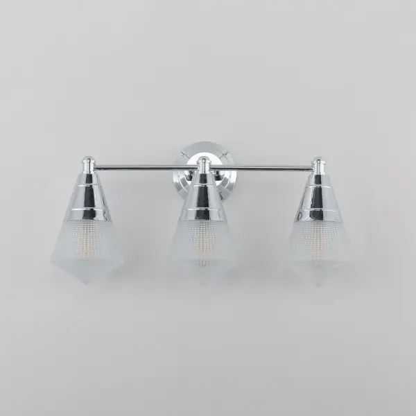 A prismatic diffusion of light is housed within pressed cone glass shades. Choose from pendants with tapered metal halves that conceal the light source or glass shades that are supported by a metal ring. Coordinating bath vanity lights complete the collection. Collection: Hargreaves Finish: Polished Chrome Glass: Prairie Rib Frost Width: 24.00" Height: 12.00" Weight: 7.40 lb Extension from Wall: 7.00" Wire: 8" Canopy: 5"x5" Number of Bulbs: 3 Maximum Wattage: 60.00 W Bulb Type: A19 Bulb Base: E26 Medium Light Source: Incandescent Dimmable Voltage: 120.00 V Material: Steel, Glass Safety Listing: cULus Safety Rating: Damp Manufacturer Warranty: 3 Spec Sheet Instructions - alternate view