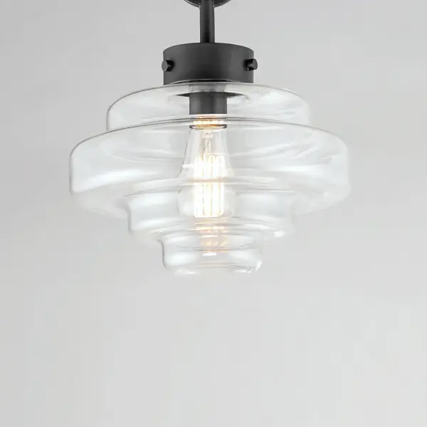 A sizable layered glass oscillates depth and is supported by three industrial set screws for support. Available as a pendant or flush mount, the pendant also features an oversized ring to evoking nautical vibes while remaining minimalist in its design. Available in Satin Nickel or Matte Black, pair the clear glass shades with a vintage filament lamps to complete the look. - alternate view