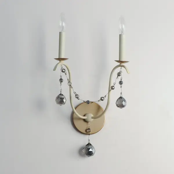 This series draws inspiration from regal agrarian manors, delivering a statement in its scale and sophisticated finishes. Designed in operatic proportions, the bottom chandelier assembly features swollen curves hand painted in a choice of Ecru White or Golden Noir and suspended by a rigid hook structure replete with vintage charm. These finish combinations not only add dimension and interest, but they are enhanced with the contrastingly brighter accents against the rich, weathered finishes. Extended chain links with smoky beveled crystal charms drape the Ecru and Gold Leaf finish combination, while the darker Golden Noir variation features strands of patinaed silver wooden beads. - alternate view