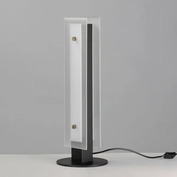 Panes of clear ribbed glass are secured with oversized knurled Natural Aged Brass pins on a Matte Black frame. Obscured by the glass texture, the integrated LED is not only soft on the eyes but also provides an abundance of illumination. Varied configurations of linear pendants, flush mounts, desk lamp, and vanity lights round out this collection. The vanity lights feature an easily accessible 5-CCT toggle switch that allows you to set different light color temperatures during or after installation. - alternate view