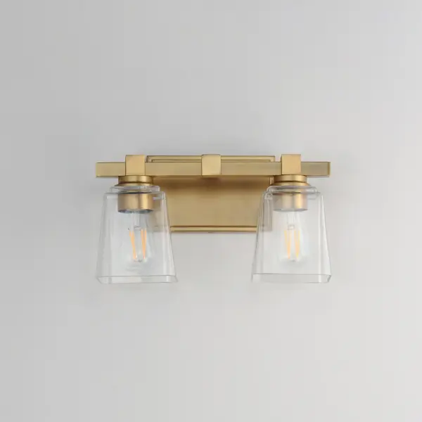A composition of square forms that feature a Clear tapered square glass shade, these bath vanities provide a transitional design that suits both modern and traditional spaces. Available in Matte Black, Polished Chrome, Satin Nickel, and Natural Aged Brass. Collection: Cubos Finish: Natural Aged Brass Glass: Clear Width: 14.00" Height: 8.00" Weight: 4.10 lb Extension from Wall: 6.00" Wire: 8" Canopy: 4.75"x7.75" Number of Bulbs: 2 Maximum Wattage: 60.00 W Bulb Type: A19 Bulb Base: E26 Medium Light Source: Incandescent Dimmable Voltage: 120.00 V Material: Steel, Glass Safety Listing: cULus Safety Rating: Damp Manufacturer Warranty: 3 Spec Sheet Instructions - alternate view