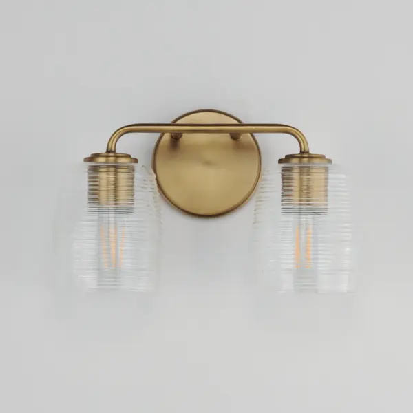 Warm and subtly nostalgic, the Honey collection draws inspiration from vintage honey jars and the familiar grooves of wooden dippers. Delicate ribbing on the clear glass shades plays with the light, creating gentle refractions that echo the soft sweetness of its namesake. Finished in either hand-brushed Kentucky Bronze or Natural Aged Brass, the frame brings an inviting glow that suits both traditional and contemporary settings. Honey lends an effortless charm to vanities, powder rooms, or anywhere you want a little golden-hour warmth--any time of day. Collection: Honey Finish: Natural Aged Brass Glass: Clear Ribbed Width: 14.00" Height: 8.25" Weight: 3.70 lb Extension from Wall: 6.00" Wire: 8" Canopy: 5"x5" Number of Bulbs: 2 Maximum Wattage: 60.00 W Bulb Type: A19 Bulb Base: E26 Medium Light Source: Incandescent Voltage: 120.00 V Material: Steel, Glass Safety Listing: cULus Safety Rating: Damp Manufacturer Warranty: 3 Spec Sheet - alternate view