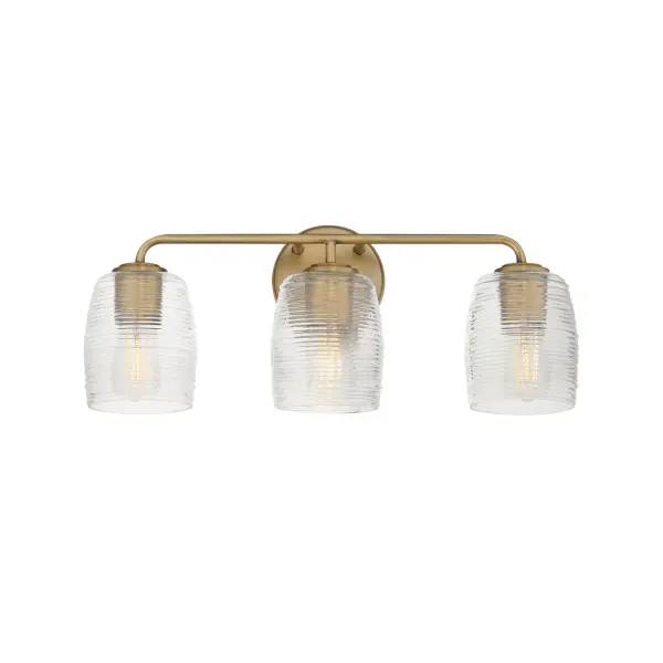 Warm and subtly nostalgic, the Honey collection draws inspiration from vintage honey jars and the familiar grooves of wooden dippers. Delicate ribbing on the clear glass shades plays with the light, creating gentle refractions that echo the soft sweetness of its namesake. Finished in either hand-brushed Kentucky Bronze or Natural Aged Brass, the frame brings an inviting glow that suits both traditional and contemporary settings. Honey lends an effortless charm to vanities, powder rooms, or anywhere you want a little golden-hour warmth--any time of day. Collection: Honey Finish: Natural Aged Brass Glass: Clear Ribbed Width: 22.00" Height: 8.50" Weight: 5.50 lb Extension from Wall: 6.00" Wire: 8" Canopy: 5"x5" Number of Bulbs: 3 Maximum Wattage: 60.00 W Bulb Type: A19 Bulb Base: E26 Medium Light Source: Incandescent Voltage: 120.00 V Material: Steel, Glass Safety Listing: cULus Safety Rating: Damp Manufacturer Warranty: 3 Spec Sheet