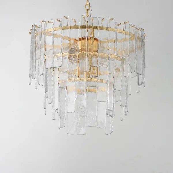 Gracefully flowing molten glass panels with uniquely organic aesthetic encircle rings of rich Darkened Bronze metal or hand-applied Gold Leaf. This refined interpretation of tiered glass pendants exudes warmth and elegance, effortlessly blending a moody ambiance with timeless contemporary charm. Available in a variety of pendant configurations as well as coordinating wall sconce and semi-flush mount. Collection: Warren Finish: Gold Leaf Glass: Artisan Width: 24.00" Height: 21.50" Length: 24.00" Weight: 41.88 lb Chain: 72" Wire: 180" Canopy: 5"x5"x1" Number of Bulbs: 9 Maximum Wattage: 60.00 W Bulb Base: E12 Candelabra Light Source: Incandescent Dimmable Voltage: 120.00 V Material: Steel, Glass Safety Listing: cETLus Safety Rating: Dry Spec Sheet Instructions - alternate view