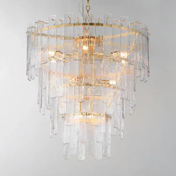 Gracefully flowing molten glass panels with uniquely organic aesthetic encircle rings of rich Darkened Bronze metal or hand-applied Gold Leaf. This refined interpretation of tiered glass pendants exudes warmth and elegance, effortlessly blending a moody ambiance with timeless contemporary charm. Available in a variety of pendant configurations as well as coordinating wall sconce and semi-flush mount. Collection: Warren Finish: Gold Leaf Glass: Artisan Width: 30.00" Height: 32.00" Length: 30.00" Weight: 74.48 lb Chain: 72" Wire: 180" Canopy: 5"x5"x1" Number of Bulbs: 12 Maximum Wattage: 60.00 W Bulb Base: E12 Candelabra Light Source: Incandescent Dimmable Voltage: 120.00 V Material: Steel, Glass Safety Listing: cETLus Safety Rating: Dry Spec Sheet Instructions - alternate view