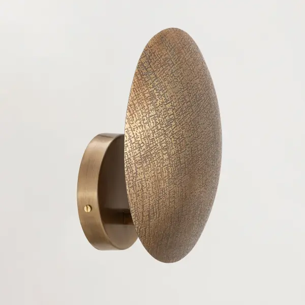 Rooted in ancient artistry and shaped for modern spaces, Aurelia is a study in timeworn opulence. Each globe pendant is formed from etched metal with a soft, tactile finish that evokes handcrafted metalwork. Finished in a warm brass tone, the shade conceals the light source entirely, casting a gentle, ambient glow that radiates from within. A black rayon cord adds a refined contrast, while a coordinating ADA-compliant backlit wall sconce completes the collection with subtle drama. Offered in multiple sizes, Aurelia brings a timeless, sculptural presence to any interior. - alternate view