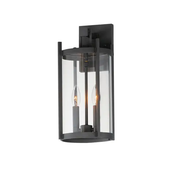 Squared columns in Matte Black finish tower above the cylindrical glass shade rated for outdoor applications. Available in a more modern clear glass option or hammered glass. A rectangular hook detail carries the square form through to the backplate. A modern interpretation of a bell tower, these outdoor pendants and sconces are a cleaned up, transitional look for exteriors.