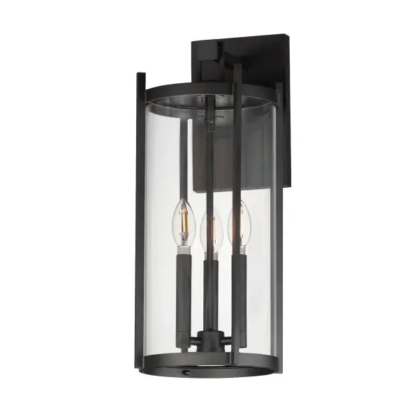 Squared columns in Matte Black finish tower above the cylindrical glass shade rated for outdoor applications. Available in a more modern clear glass option or hammered glass. A rectangular hook detail carries the square form through to the backplate. A modern interpretation of a bell tower, these outdoor pendants and sconces are a cleaned up, transitional look for exteriors.
