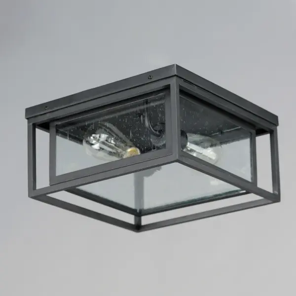 A dual framed structure creates dimension on these outdoor lighting fixtures that is both contemporary and transitional. The construction consists of two frames of square tubing and squared components. The inner frame's Clear Seedy glass reduces glare from the light and appears dirt-free for longer periods. This is a comprehensive collection to brighten all areas of your outdoor space, available in various sized sconces as well as hanging and post configurations. - alternate view