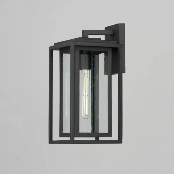 A dual framed structure creates dimension on these outdoor lighting fixtures that is both contemporary and transitional. The construction consists of two frames of square tubing and squared components. The inner frame's Clear Seedy glass reduces glare from the light and appears dirt-free for longer periods. This is a comprehensive collection to brighten all areas of your outdoor space, available in various sized sconces as well as hanging and post configurations. - alternate view