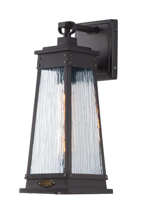A tapered square shade finished in Olde Brass suspends from a bracket to replicate a nautical lantern. Panels of clear Ripple glass allow for the lamp to shine through while still diffusing the light. The medallion at the base of the shade and rivets along the frame are finished in an antique brass to add authenticity to the design.