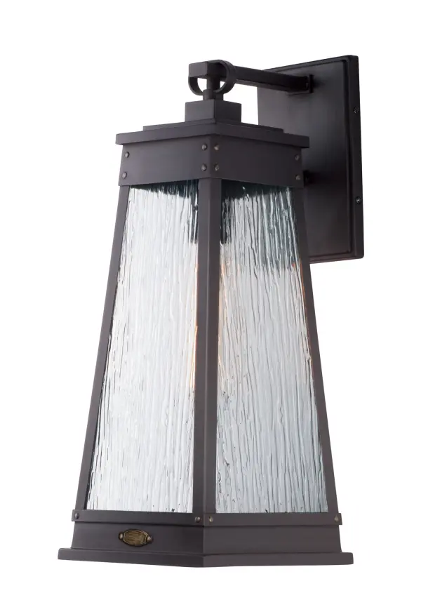 A tapered square shade finished in Olde Brass suspends from a bracket to replicate a nautical lantern. Panels of clear Ripple glass allow for the lamp to shine through while still diffusing the light. The medallion at the base of the shade and rivets along the frame are finished in an antique brass to add authenticity to the design.