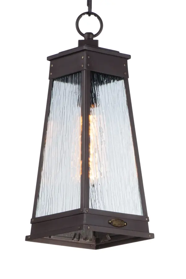 A tapered square shade finished in Olde Brass suspends from a bracket to replicate a nautical lantern. Panels of clear Ripple glass allow for the lamp to shine through while still diffusing the light. The medallion at the base of the shade and rivets along the frame are finished in an antique brass to add authenticity to the design.