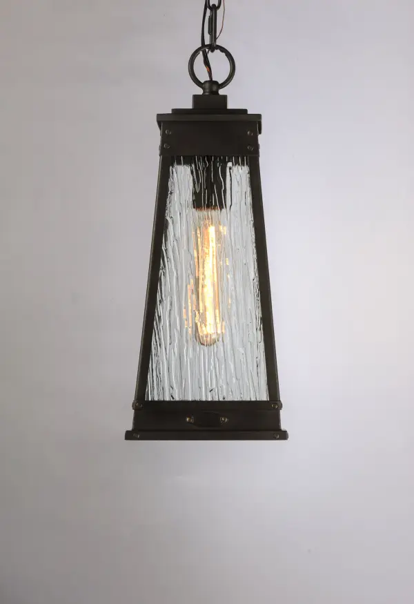 A tapered square shade finished in Olde Brass suspends from a bracket to replicate a nautical lantern. Panels of clear Ripple glass allow for the lamp to shine through while still diffusing the light. The medallion at the base of the shade and rivets along the frame are finished in an antique brass to add authenticity to the design. - alternate view