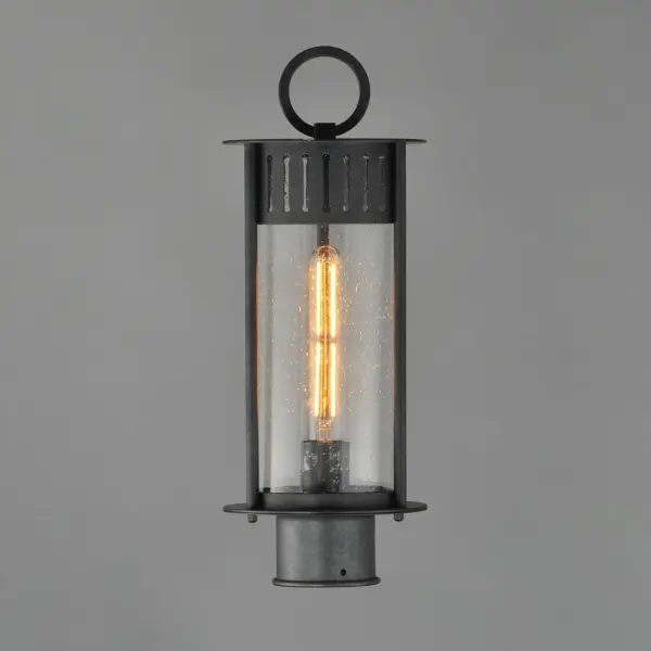 Inspired by the rounded towers of Windsor Castle, this outdoor lighting collection features a hand-applied Black Patina finish on Stainless Steel. A slotted filigree along the top of the cylinder frame allows light to escape, while the clear seeded glass obscures the light source enough to soften the glare a light bulb casts. - alternate view