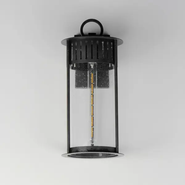 Inspired by the rounded towers of Windsor Castle, this outdoor lighting collection features a hand-applied Black Patina finish on Stainless Steel. A slotted filigree along the top of the cylinder frame allows light to escape, while the clear seeded glass obscures the light source enough to soften the glare a light bulb casts. - alternate view