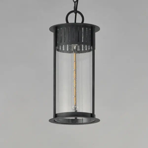Inspired by the rounded towers of Windsor Castle, this outdoor lighting collection features a hand-applied Black Patina finish on Stainless Steel. A slotted filigree along the top of the cylinder frame allows light to escape, while the clear seeded glass obscures the light source enough to soften the glare a light bulb casts. - alternate view