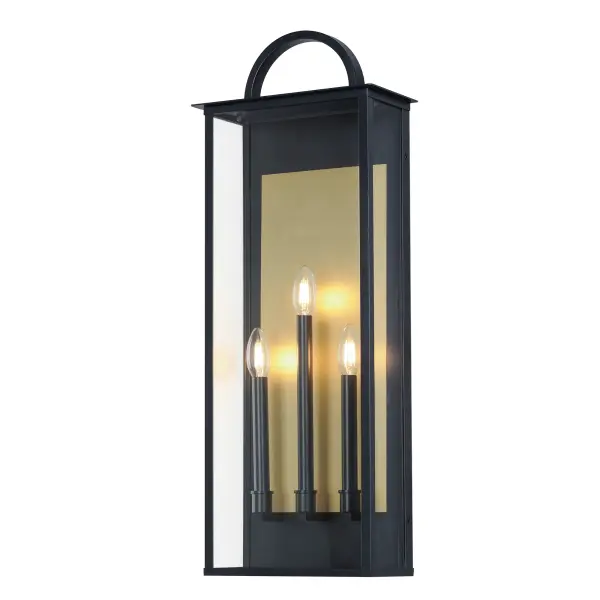The Manchester series is inspired by classic coach lanterns and consists of minimally extended sconces in a variety of sizes that have been modified with simplified embellishments. The black frames have been modified with a squared arc handle and a contrasting Burnished Gold plate that reflects clusters of candle lights surrounded by Clear glass panels. This collection references historic exterior sconces while modernizing their appearance. Complement the design with tubular lamps to accentuate the verticality of the frames.
