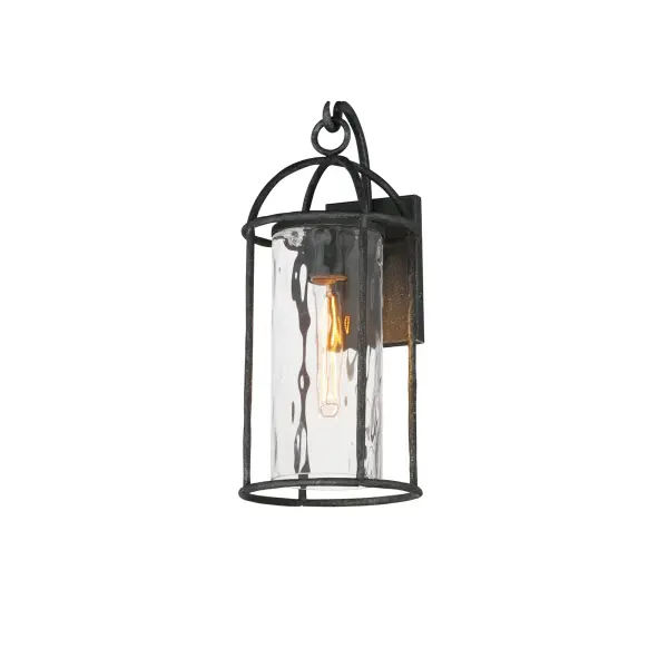 Inspired by classic European lanterns and handcrafted ironwork, the Del Mar collection brings timeless sophistication to exterior spaces. Its airy open-frame silhouette is crafted of hammered iron, elegantly arched with a graceful hook detail that nods to historic gas lamps. Inside the frame, a delicate Water glass cylinder shimmers with texture, diffusing light in a soft, atmospheric glow. Designed for lasting beauty in the elements, each piece is finished in a richly layered Blacksmith finish--a deep near-black tone highlighted by silvery brushstrokes, adding artisanal character to the silhouette. Whether flanking a grand entry or lining a garden path, Del Mar offers a refined approach to outdoor lighting with enduring presence.